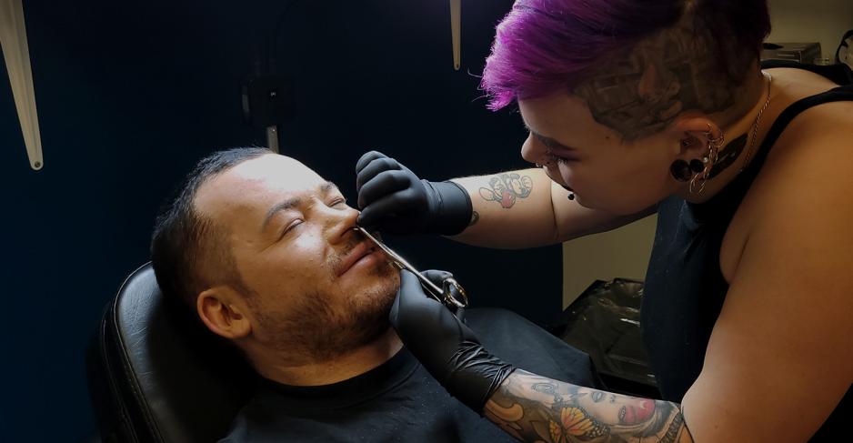 Mann som f&aring;r piercing i ansiktet.