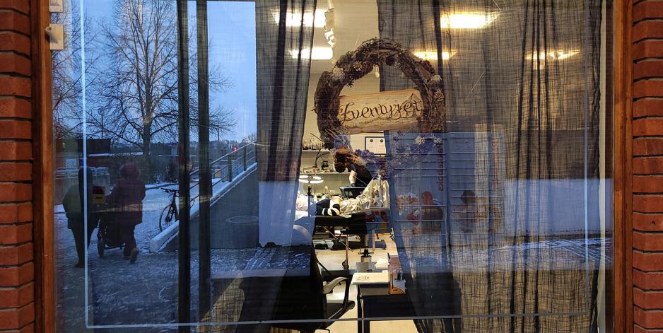 Eit vindu inn mot eit tatoveringsstudio, der det heng ein krans med logo.