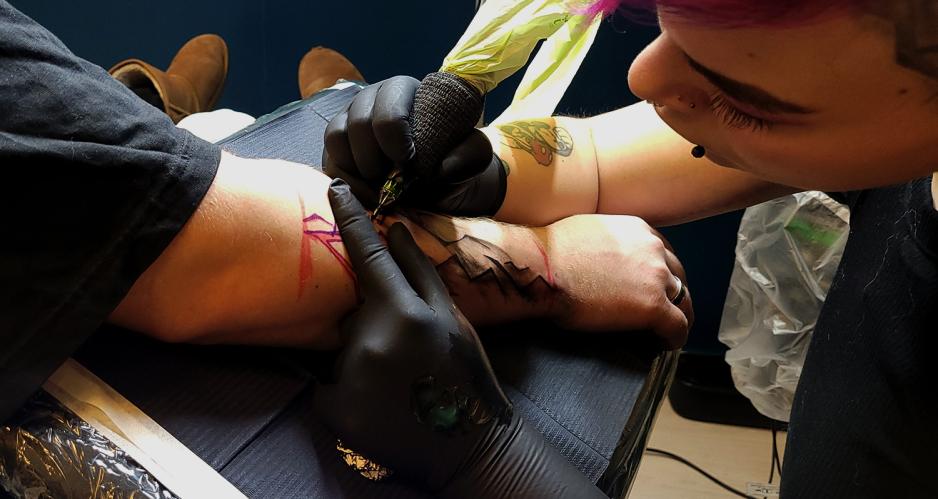 Ei dame tatoverar eit lyn p&aring; ein arm. 