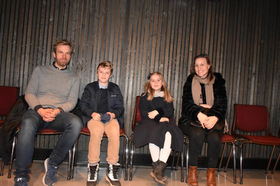 En familie p&aring; fire sitter p&aring; hver sin stol foran en vegg. Til venstre en mann i gr&aring; genser. Han er blond med litt skjegg. I midten sitter de to barna, en gutt p&aring; 11 og ei jente p&aring; 7 &aring;r. De har pyntet seg. Moren, en brunette, sitter p&aring; h&oslash;yre side. 