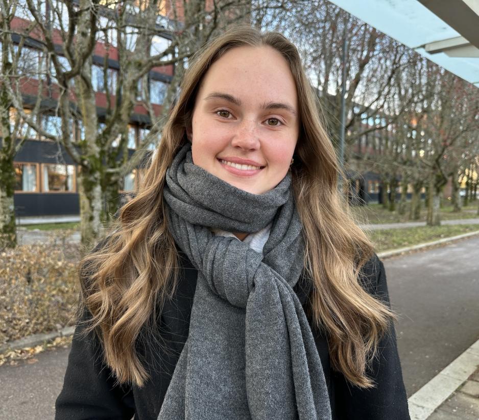 En jente med m&oslash;rkt h&aring;r som smiler mot kamera