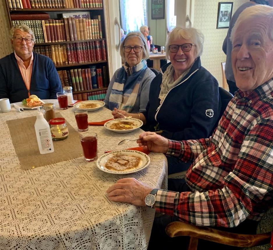 Fire eldre sitter rundt et bord og spiser gr&oslash;t