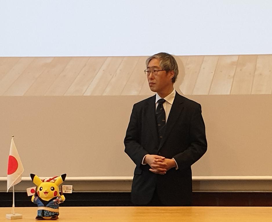 Japansk mann st&aring;r ved siden av pikachu kosedyr