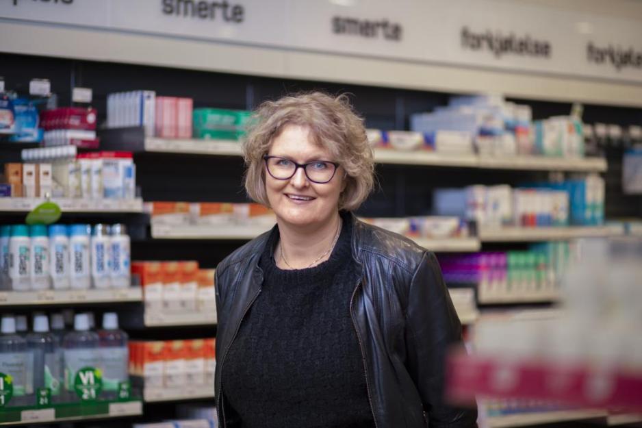 Middelaldrende kvinne foran legemidler p&aring; et apotek.