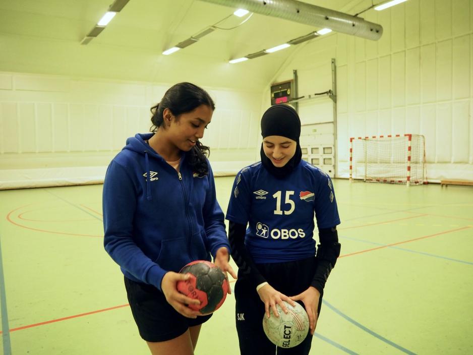 To h&aring;ndballspillere ser ned p&aring; h&aring;ndballene de holder i hendene sine.