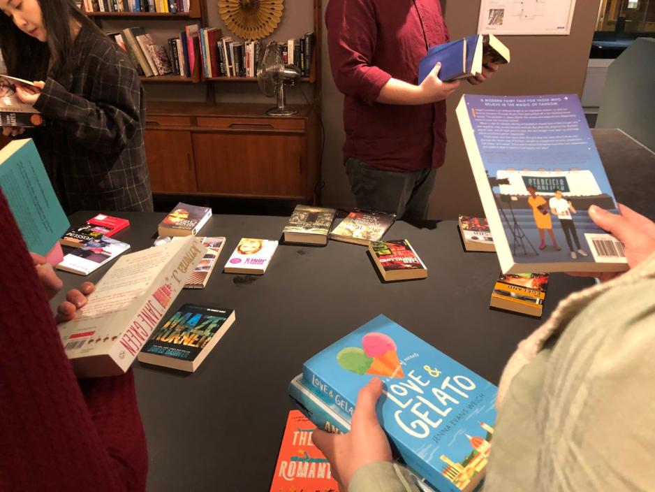 To personer holder b&oslash;ker foran et bord med b&oslash;ker