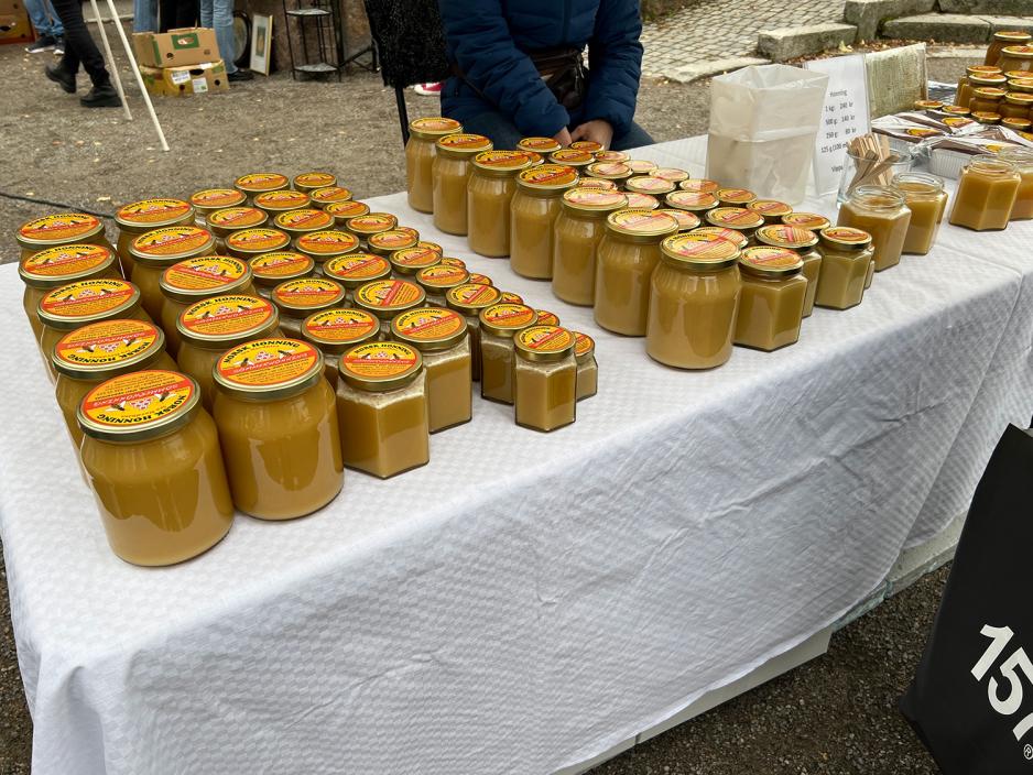 Mange krukker med lys honning p&aring; en hvit duk