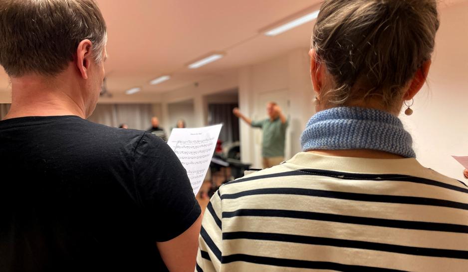 Bildet viser en mann som holder et noteark med sangen "Hurra for deg" p&aring;. 