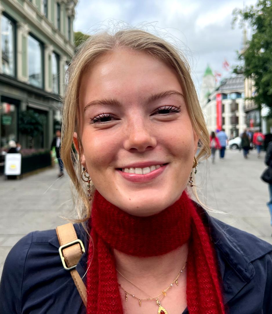 Bilde av Ida Apenes med blondt h&aring;r, stort smil, med r&oslash;dt skjerf og bl&aring; topp