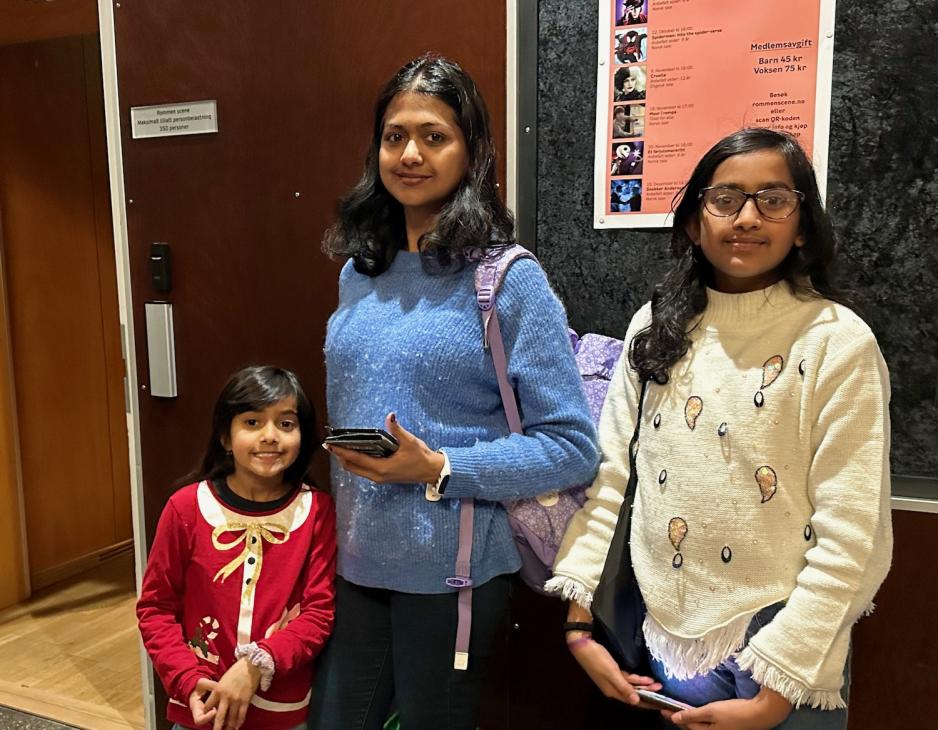 Mor og to d&oslash;tre som st&aring;r p&aring; utsiden av lokalet der forestillingen fant sted. 