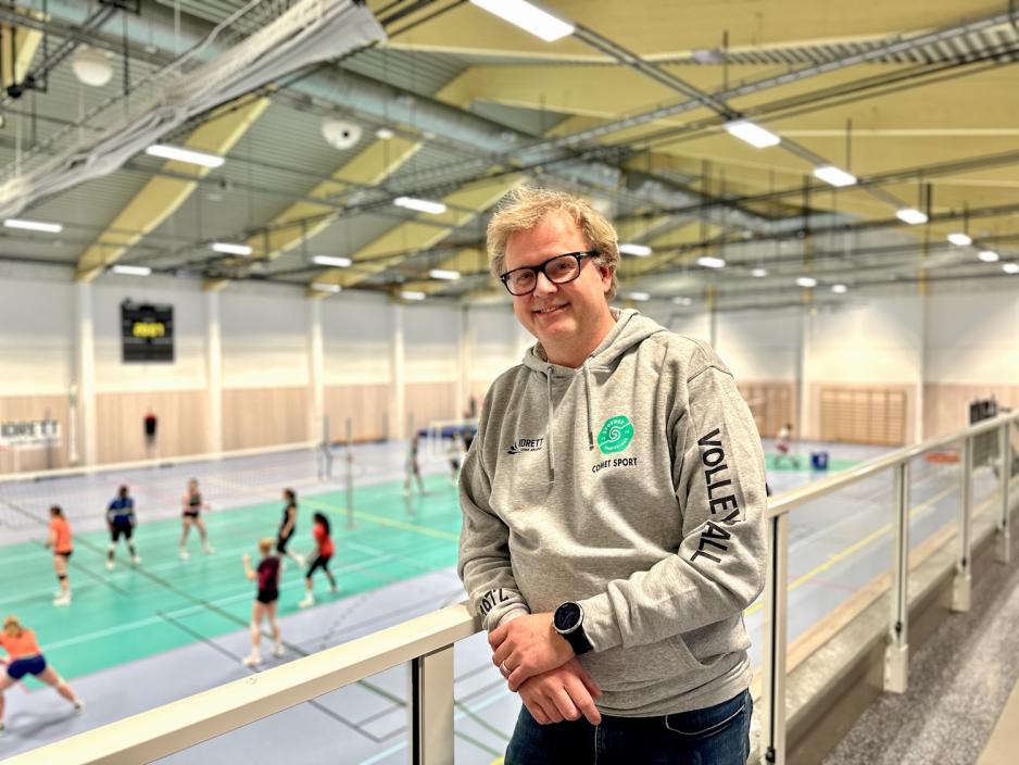 Tor Simonn&aelig;s i Stovnerhallen med mange ungdommer i bakgrunn som spiller volleyball.