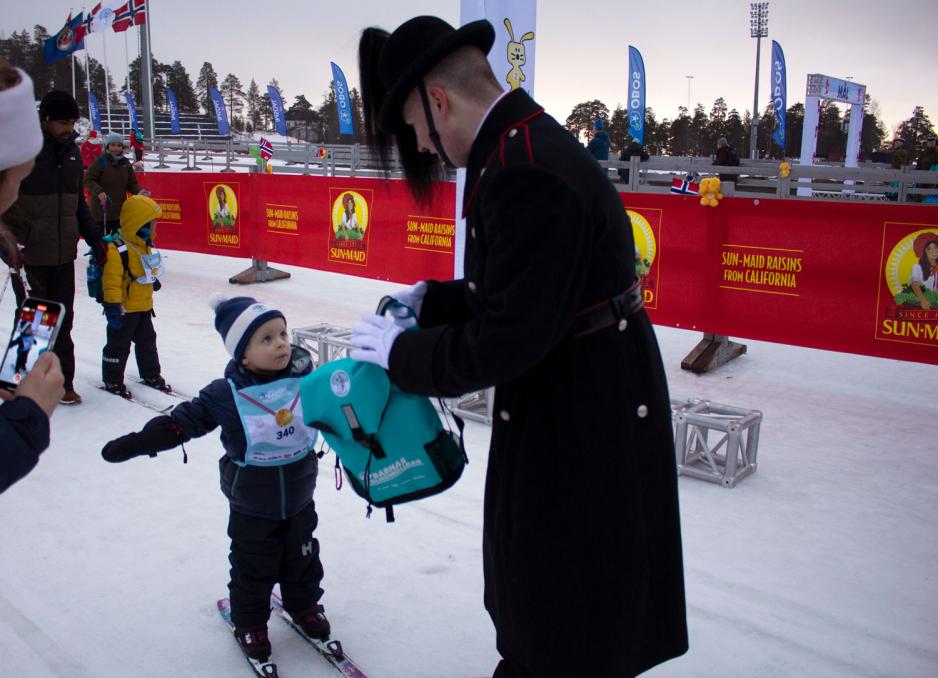 Gutt som har g&aring;tt i m&aring;l p&aring; Barnas Holmenkolldag. Han mottar premie fra en gardist.