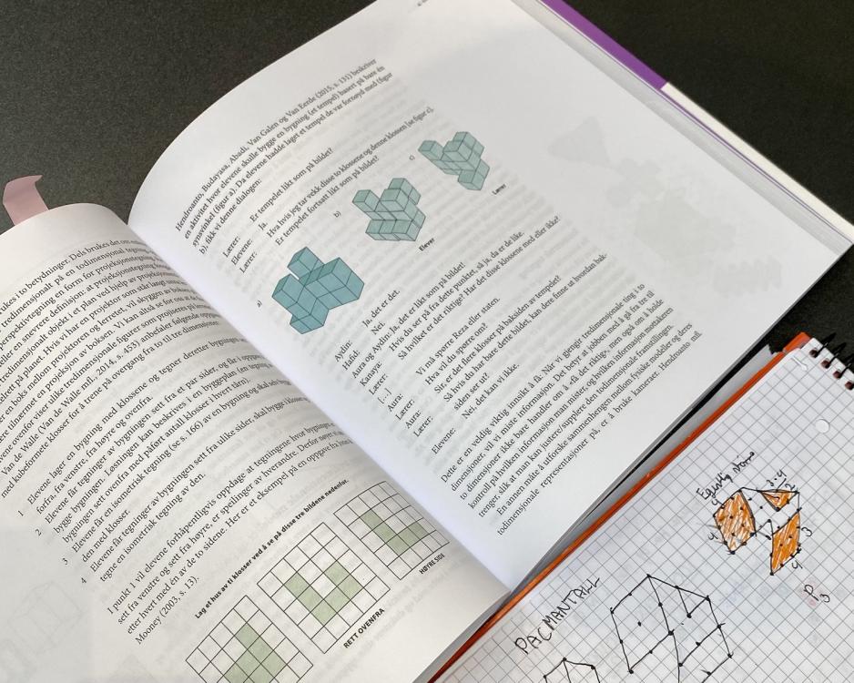 En pensumbok og en skrivebok p&aring; et bord