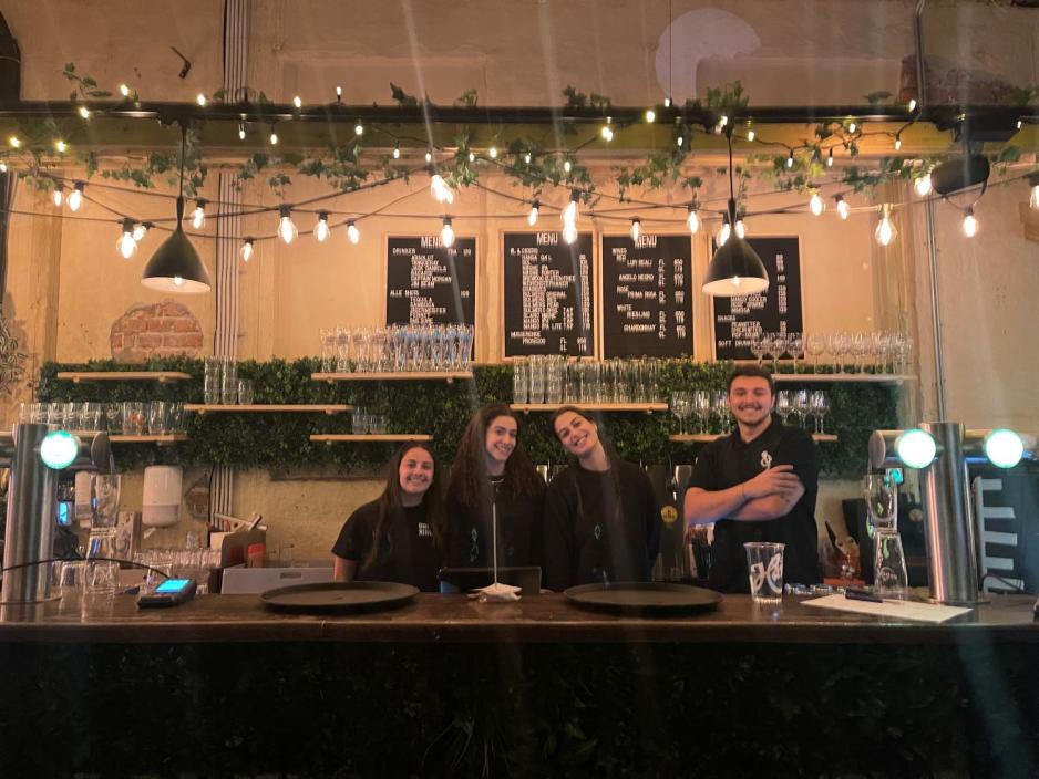 Fire smilende servit&oslash;rer st&aring;r i baren