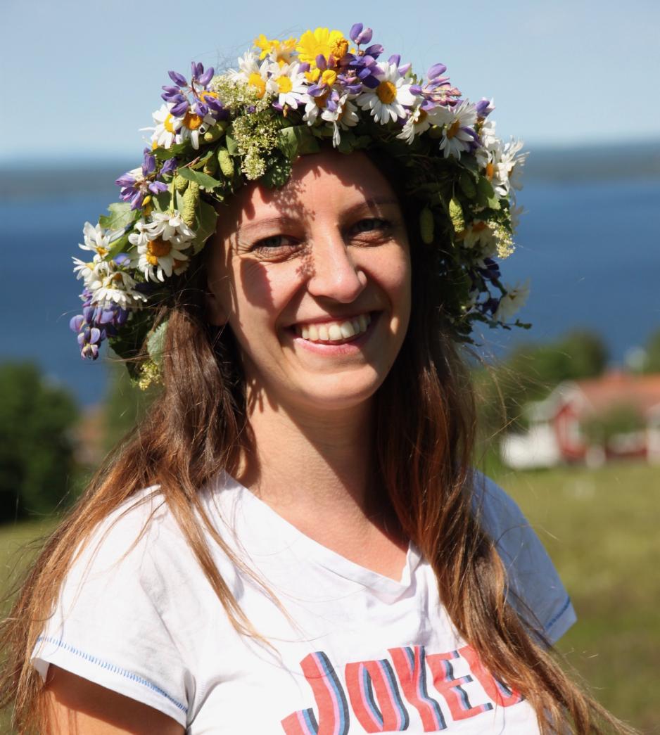En smilende Hanne Marit Tobiassen med blomsterkrans p&aring; hodet