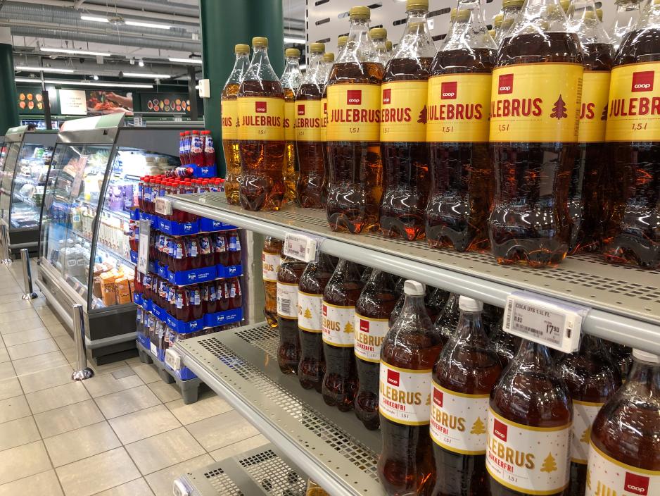 Flere rekker med julebrus st&aring;ende i en butikk.