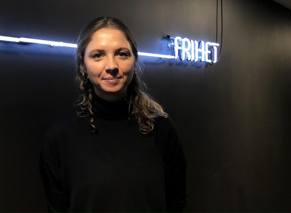 Ingrid Stolpestad foran et hvitt neonskilt der det st&aring;r frihet.