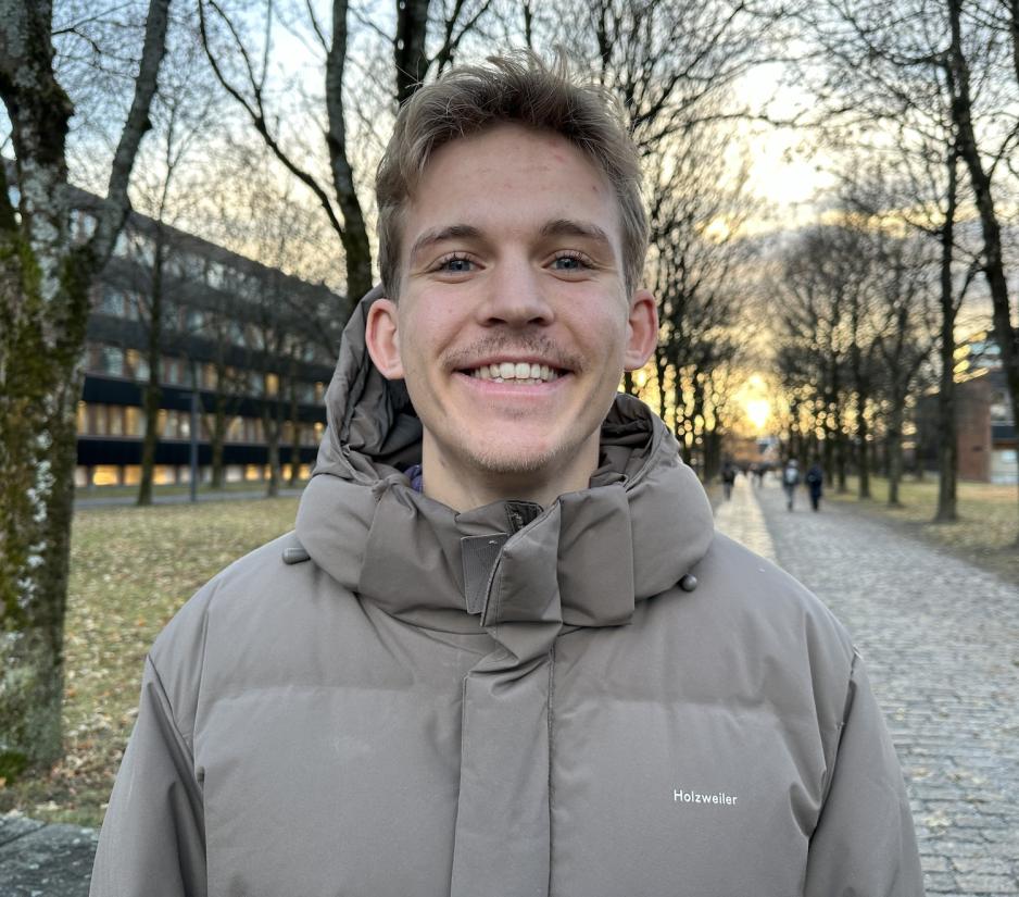 En gutt med m&oslash;rkt h&aring;r som smiler mot kamera