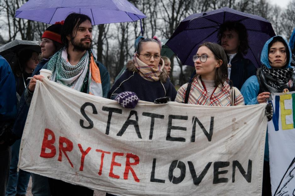 Tre stykker holder et demonstrasjonsbanner hvor det st&aring;r "Staten bryter loven"