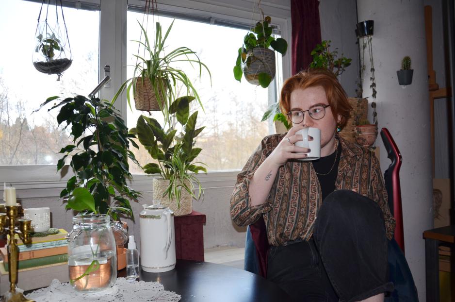 June Kittelsen sitter ved bordet p&aring; hybelen sin med en kaffekopp