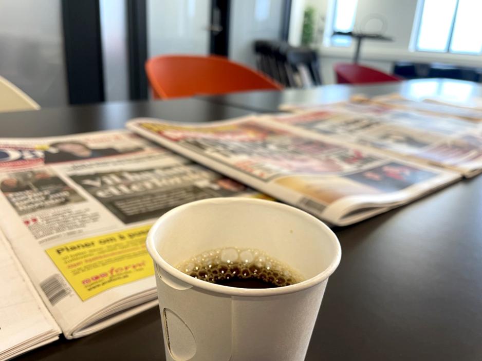 en kopp kaffe foran dagens aviser p&aring; bordet