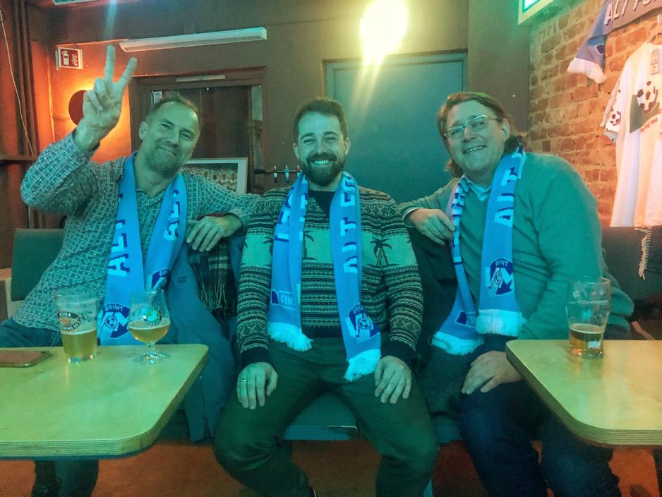 tre venner som drikker &oslash;l og smiler til kamera