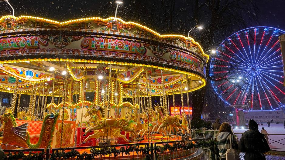 En gullfarget karusell med sk&oslash;ytebane i bakgrunnen 