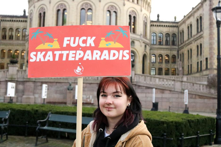 En jente som holder en plakat der det st&aring;r "F*** skatteparadis"