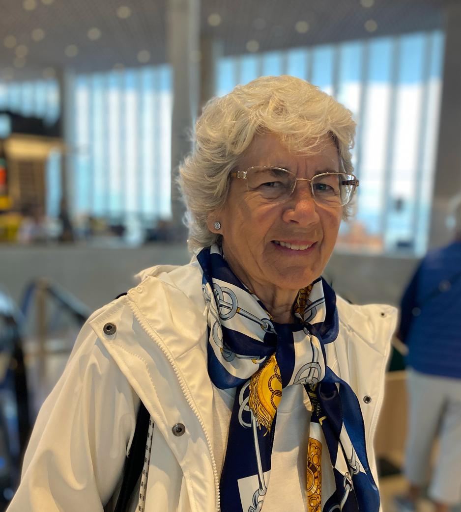 Portrett av Kerstin Ness. Hun har kort h&aring;r og briller, og en hvit ytterjakke med et silkeskjerf inni.