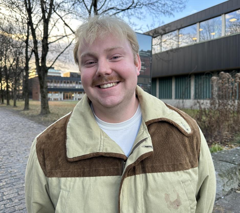 En gutt med blondt h&aring;r som smiler mot kamera