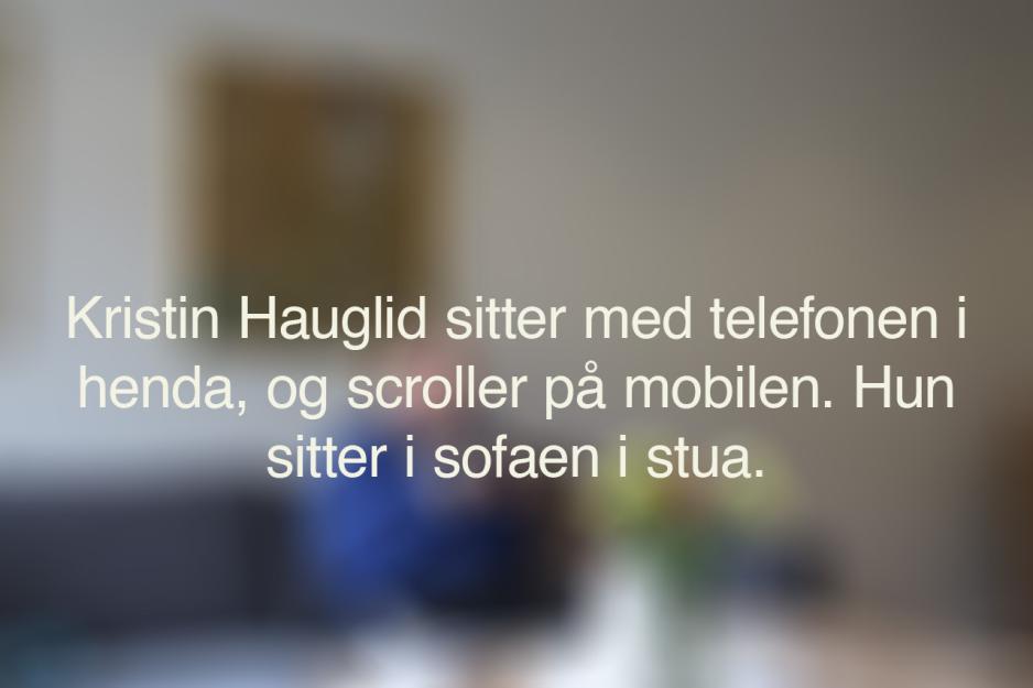 Et uskarpt bilde med den alternative teksten til bildet under. Teksten sier: Kristin Hauglid sitter med telefonen i henda, og scroller p&aring; telefonen. Hun sitter i sofaen i stua.