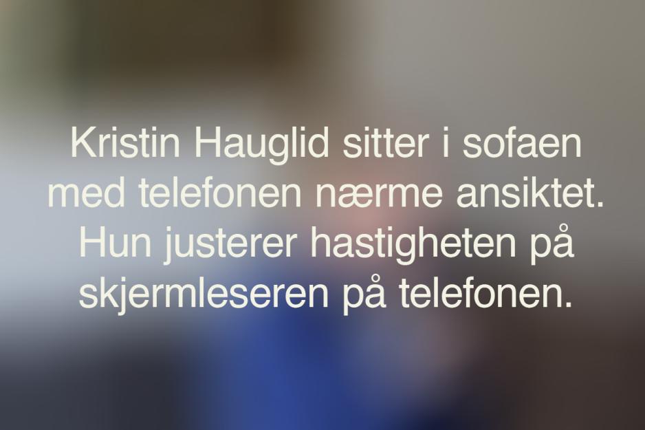 Et uskarpt bilde med den alternative teksten til bildet under. Teksten sier: Kristin Hauglid sitter i sofaen, med telefonen n&aelig;rme ansiktet. Hun justerer hastigheten p&aring; skjermleseren p&aring; telefonen.