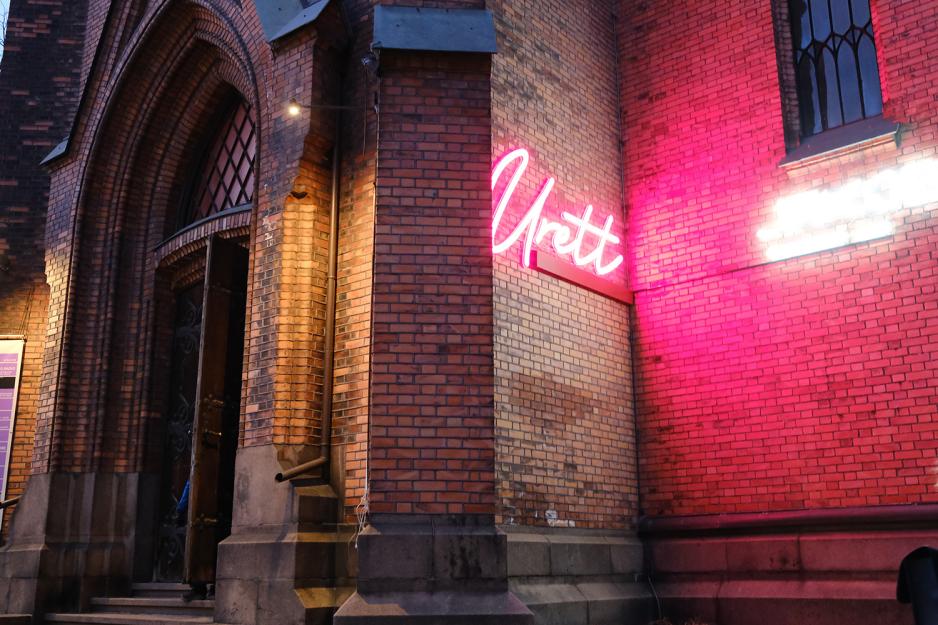 Bilde av inngangen til Kulturkirken Jakob, og noe av bygget rundt, f&oslash;r st&oslash;ttekonsert. Det er et murbygg. Et rosa, gl&oslash;dende skilt p&aring; kirken sier &laquo;urett&raquo;. 