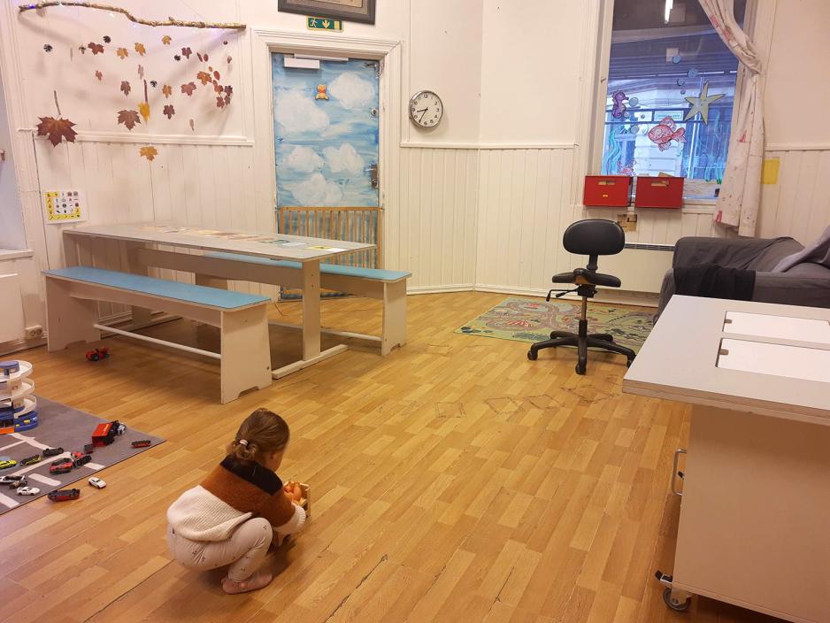 Lekerom med bord og benker. Stort gulvareal. P&aring; gulvet er en liten jente.