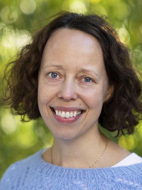 Lena Henriksen har brunt h&aring;r og smiler til kameraet.