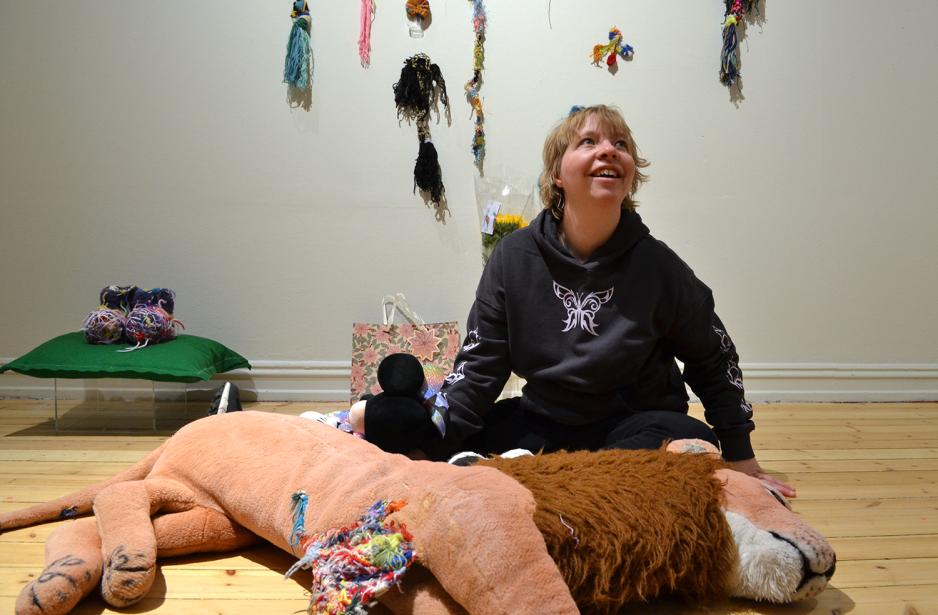 Miriam Karlsen sitter ved siden av en bamsel&oslash;ve som hun har sydd i.