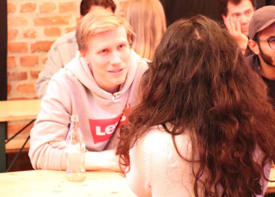 En gutt med bl&aring; &oslash;yne og hettegenser snakker med en jente med kr&oslash;llete h&aring;r. 