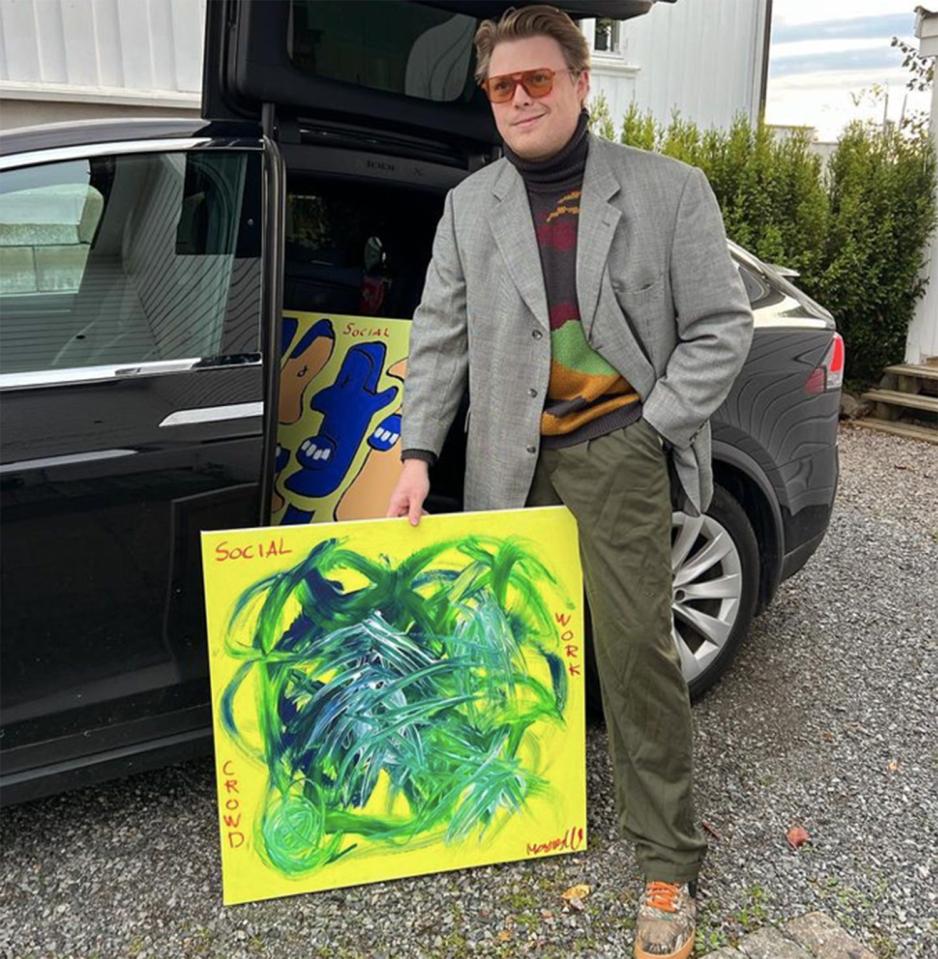 Mann st&aring;r med maleri foran bil