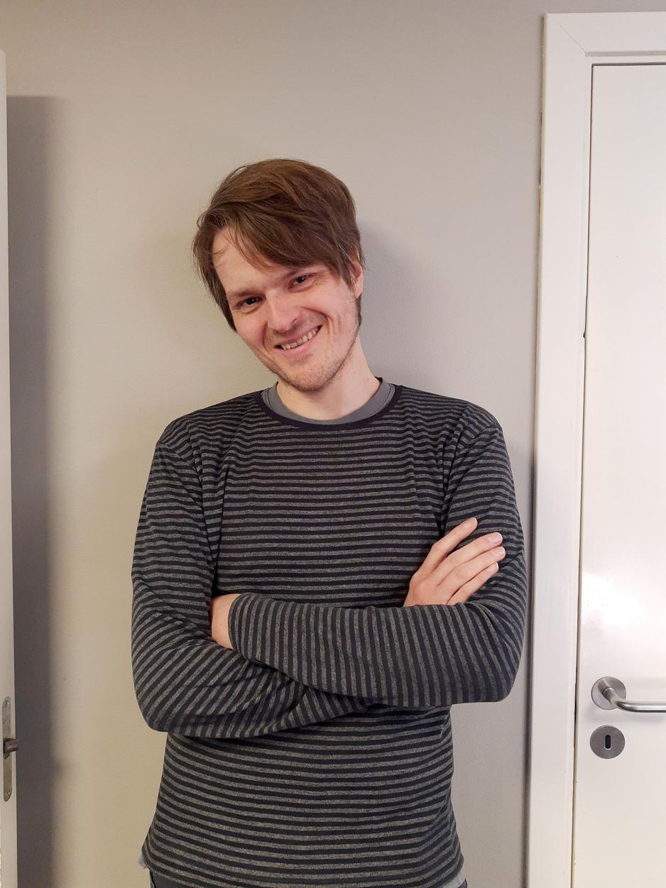 Mann st&aring;r med armene i kryss foran en d&oslash;r.