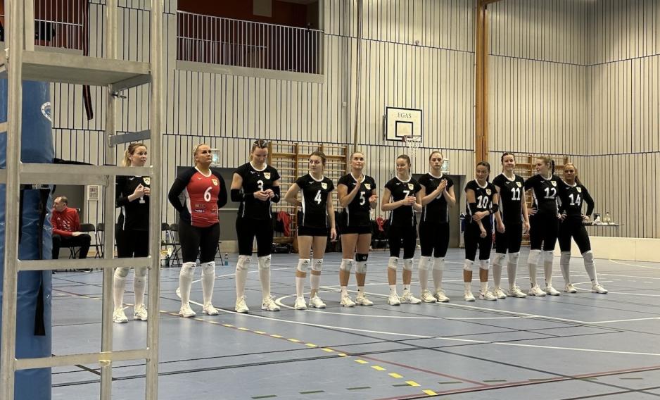 Et volleyball lag som st&aring;r p&aring; rekke i en gymsal