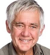 Mann med gr&aring;tt h&aring;r smiler stort.