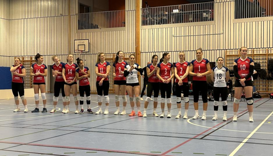 Et volleyball lag som st&aring;r p&aring; rekke i en gymsal