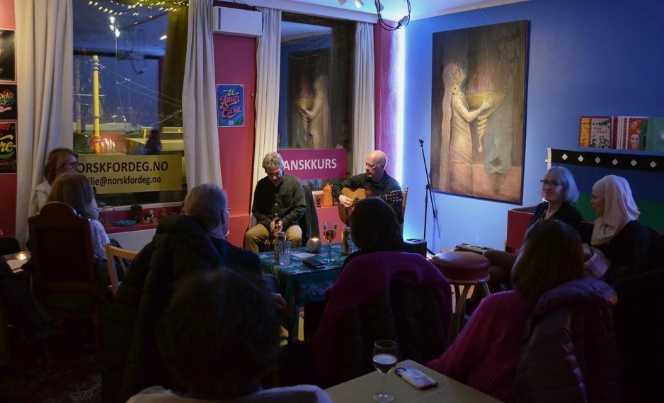 To musikere synger og spiller gitar foran et publikum. 