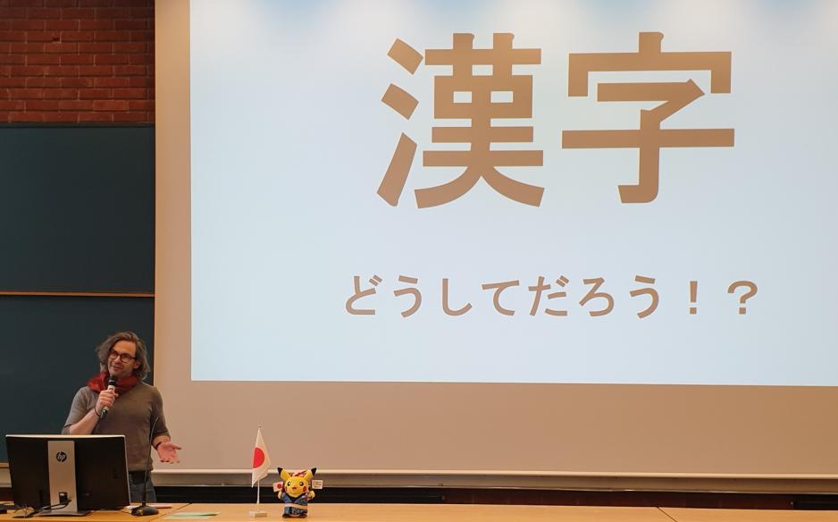 Man st&aring;r foran en power point med japansk skrift
