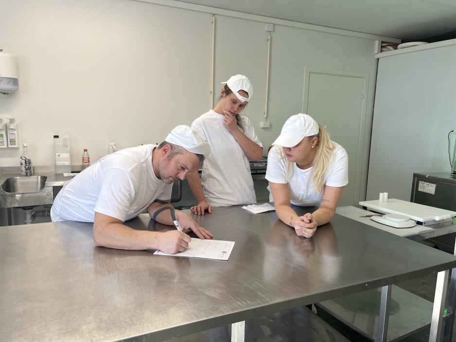 Arbeidere p&aring; ysteri ser p&aring; et papir p&aring; pakkerommet.