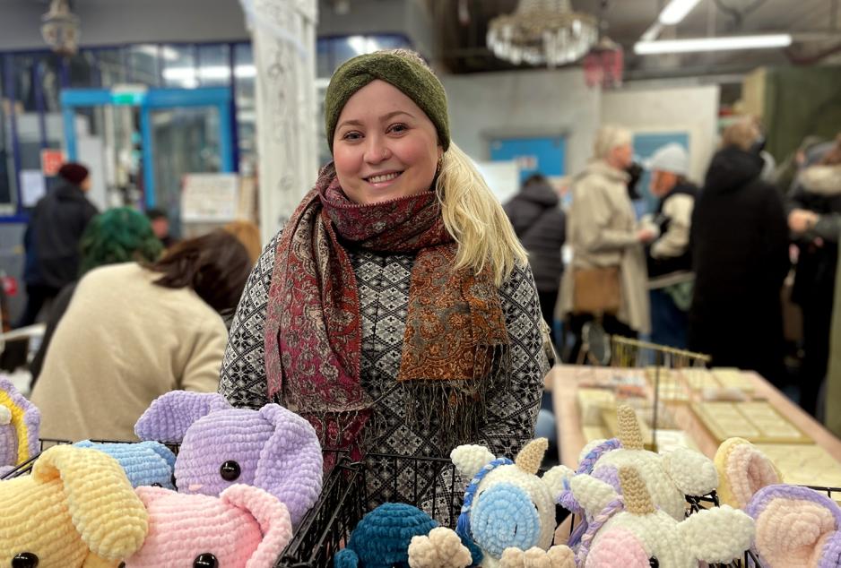 Bildet viser en smilende Pernille Olesen. Bildet er tatt inne i et lokale p&aring; markedet i Ingensgate. Hun er omringet av andre engasjerte selgere.