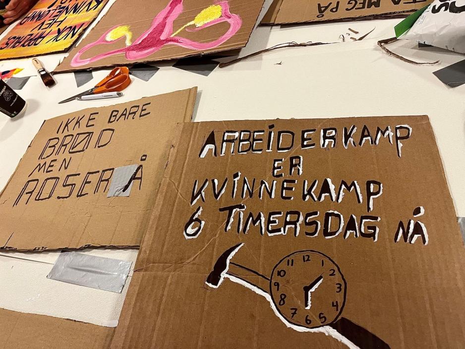 bilde av plakater med en plakat i front hvor det st&aring;r "arbeiderkamp er kvinnekamp, 6 timers dag n&aring;".