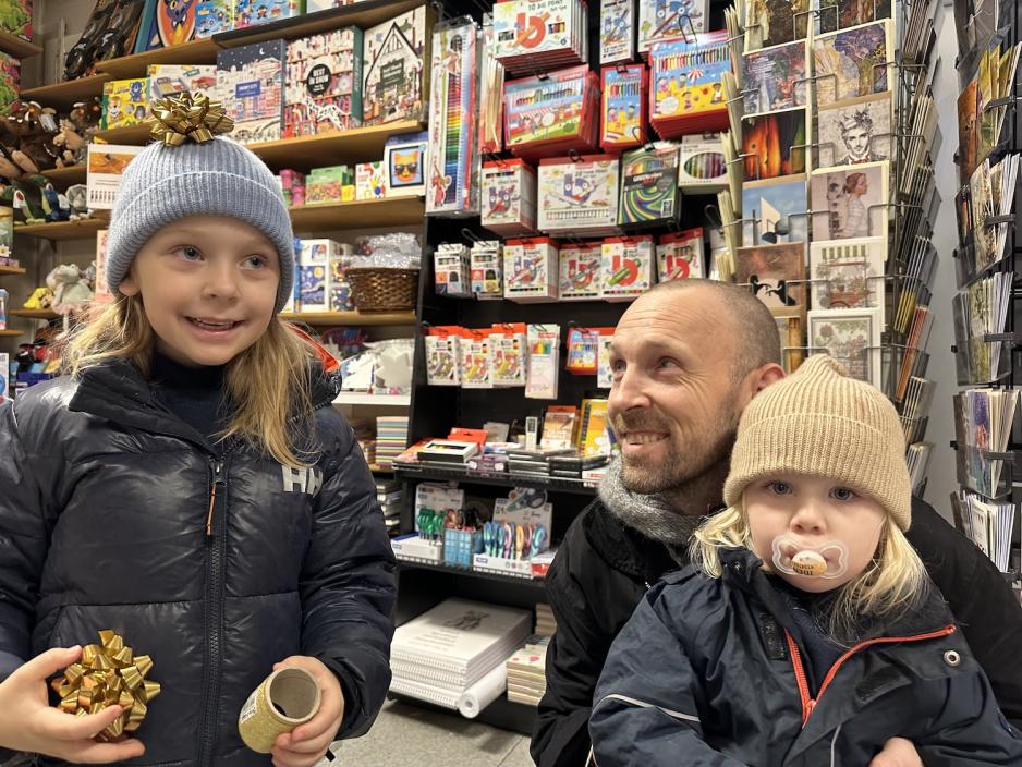 En far med sine to d&oslash;tre inne i bokhandelen