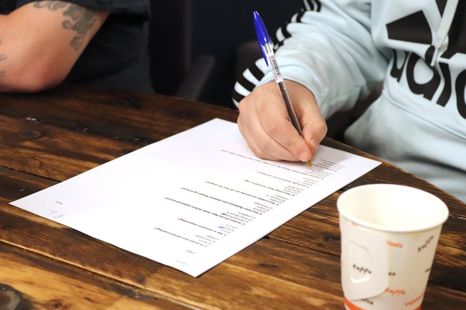 En h&aring;nd krysser av p&aring; et ark med sp&oslash;rsm&aring;l.