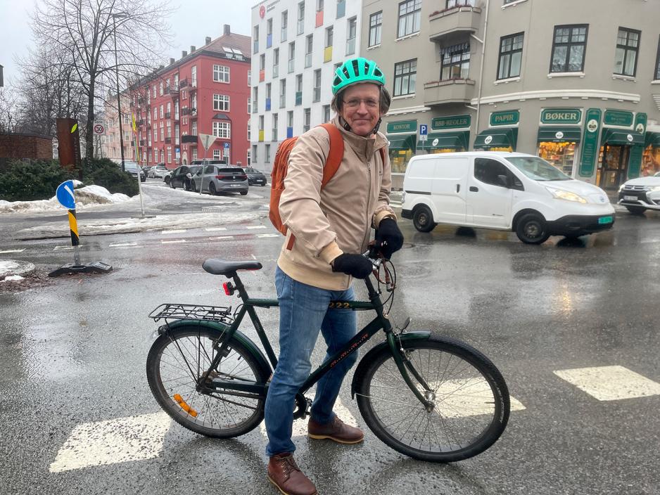 Mann med sykkel og sykkelhjelm midt p&aring; gata